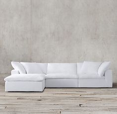 a white couch sitting on top of a wooden floor next to a gray concrete wall