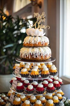 a three tiered cake with cupcakes on top