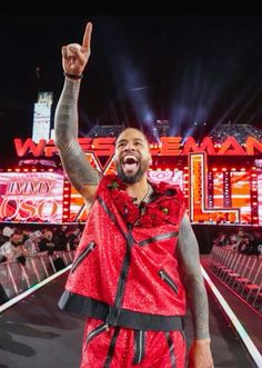 a man in a red outfit is holding his hand up