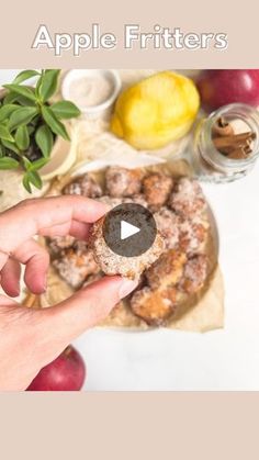 a person holding an apple fritters in front of some apples and other fruits