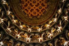 the inside of a large building with many lights on it's ceiling and an intricately designed dome