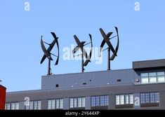 three metal sculptures on top of a building in front of a blue sky - stock photo