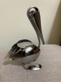 a silver bird sculpture sitting on top of a chair next to a wall and floor