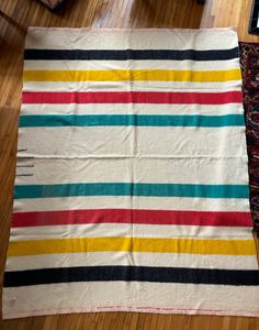 a multicolored striped rug sitting on top of a wooden floor