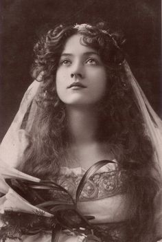 an old black and white photo of a woman with long hair wearing a wedding veil