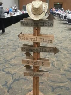 a wooden sign with many signs on it and a cowboy's hat on top