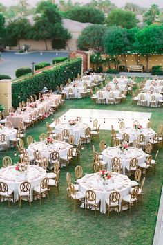 an outdoor wedding reception setup with tables and chairs set up in the middle of a lawn