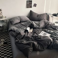 an unmade bed in a bedroom with black and white checkered flooring