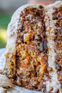 a slice of carrot cake on a white plate with some frosting and walnuts