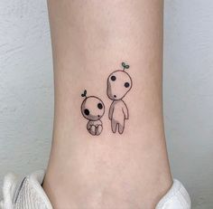 a small tattoo on the ankle of a woman's foot with an alien and baby