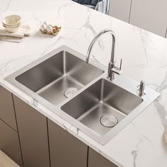 two stainless steel sinks in a kitchen with marble counter tops