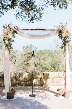 an outdoor ceremony setup with white drapes and flowers