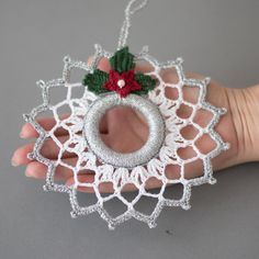 a crocheted christmas ornament hanging on a gray surface with a red and green decoration