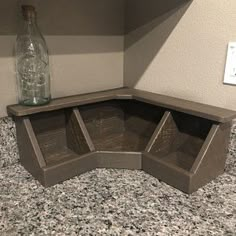 a corner shelf with two empty glass bottles on the top and one empty bottle in the bottom