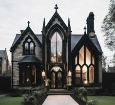 a gothic - style house with large windows and stone steps leading up to the front door