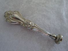 an ornate silver handle on a white cloth