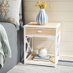 a blue and white vase sitting on top of a small table next to a bed