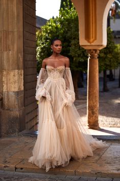 a woman in a wedding dress is walking down the street wearing an off - shoulder gown