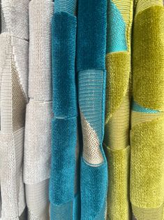 several towels are hanging on the wall in different colors and patterns, including blue, green, yellow, and white