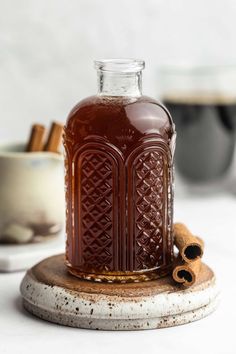 a glass bottle filled with liquid sitting on top of a wooden stand next to some cinnamons