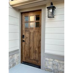 a wooden door on the side of a house with a light hanging from it's side