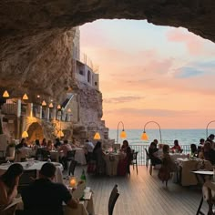 a group of people sitting at tables near the ocean