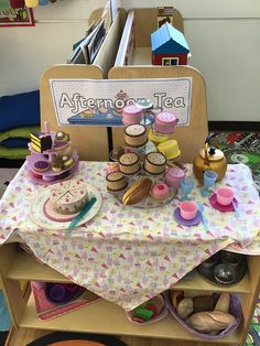 a table topped with lots of cupcakes on top of a wooden shelf next to a sign that says afternoon tea