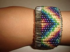 a close up of a person's arm wearing a bracelet with multicolored beads