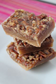 three pieces of pecan bar stacked on top of each other in front of a pink and white table cloth