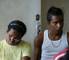 a man and woman sitting next to each other looking at something on the table in front of them