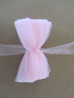 a pink tulle bow tied to a piece of white organ ribbon on a beige background