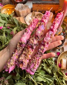 the person is holding two sticks with food on them in their hands, surrounded by flowers and candles