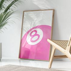 a pink poster with the number eight on it next to a chair and potted plant