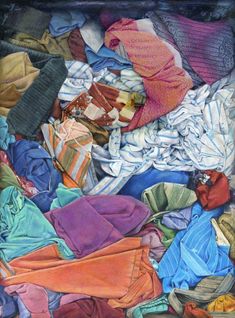 a pile of clothes sitting on top of a bed next to a pillow and blanket