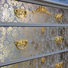 a gold and silver dresser with ornate designs on the front, drawer handles and knobs