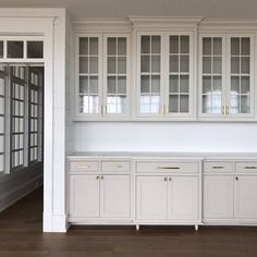 an empty kitchen with white cabinets and wood floors