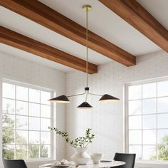 a dining room with white walls and wooden beams, black chairs and a round table