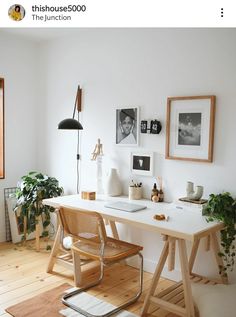 a white desk with some plants and pictures on the wall