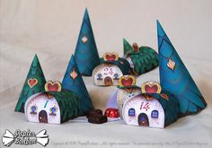 several paper houses with trees on them and candy in the bottom one is shaped like santa's house