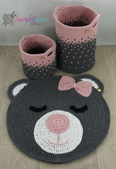 a crocheted teddy bear rug and two baskets on the floor with one bear's face