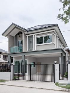 a large house with a black gate and white fenced in area next to it