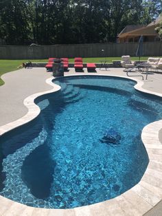 an empty swimming pool with lounge chairs around it