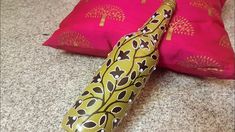 two pillows and a decorative vase on the floor in front of a pink pillow cover