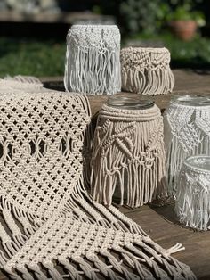 crocheted vases and jars are sitting on a wooden table in the sun