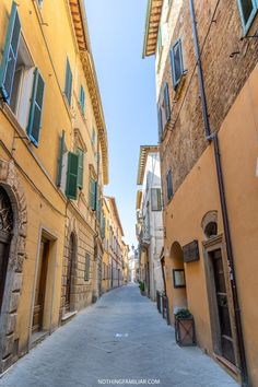 an alley way with buildings and green shutters on both sides, in the middle of town