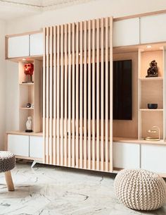 a living room with white walls and wooden slatted partitions on the wall