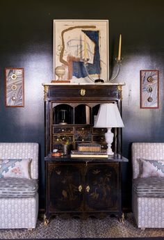 a room with two chairs and a table in it, next to a painting on the wall