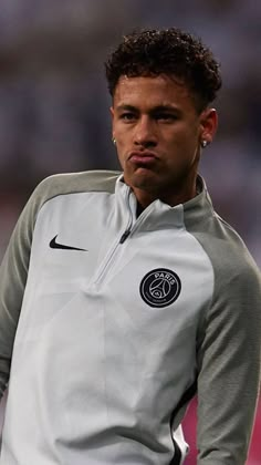 a soccer player wearing a gray and black uniform with his head turned to the side