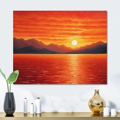 an orange sunset over the ocean with mountains in the background