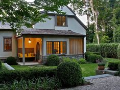 a house with landscaping in front of it and trees around the outside area that has hedges on both sides